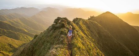 Woman walking a ridge path in the hills at golden hour